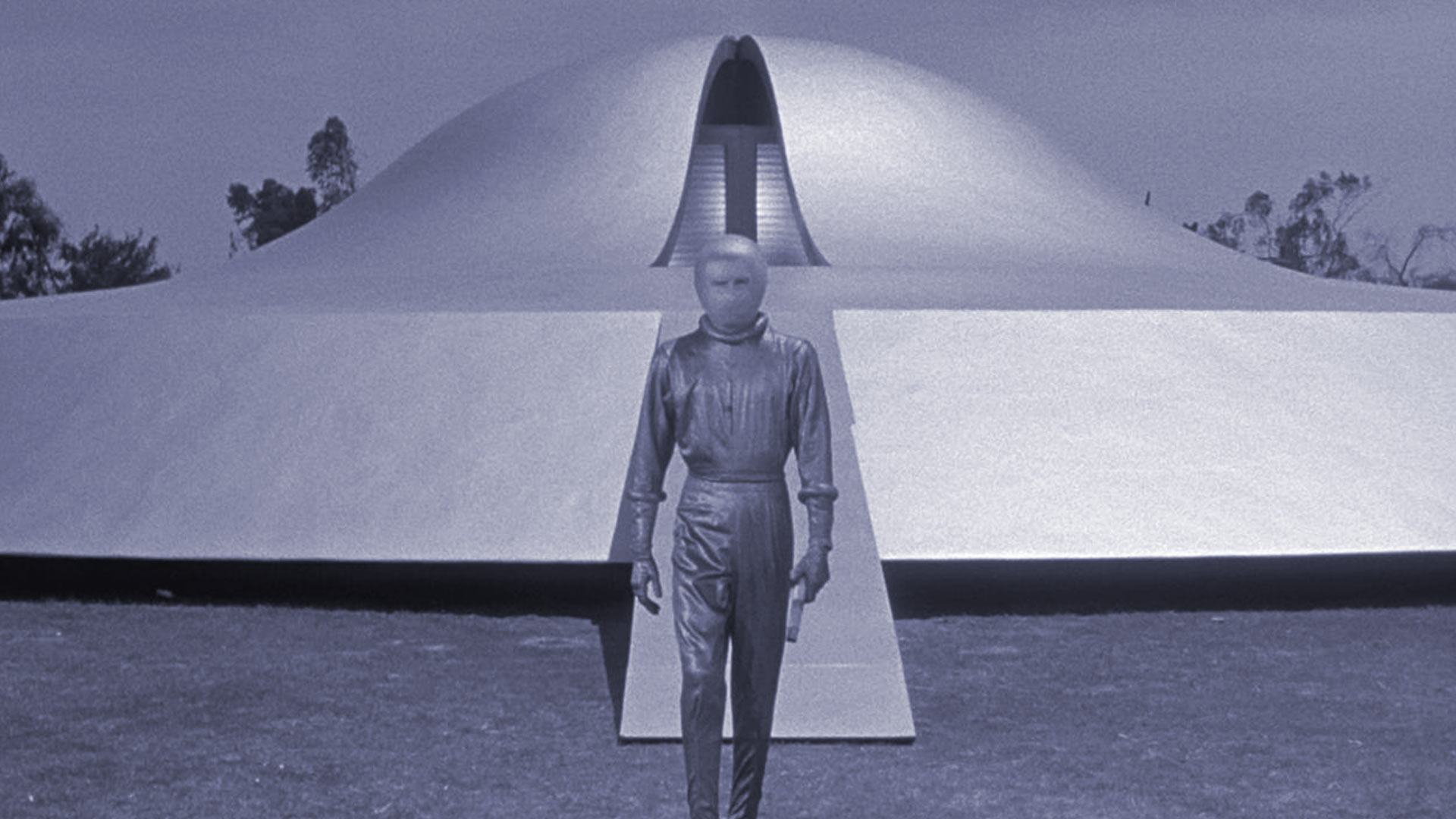 Scene from The Day the Earth Stood Still (1952) - a silver-suited alien figure stands before a flying saucer